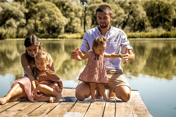 Молодая семья на пирсе у озера — стоковое фото