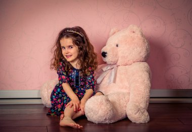 küçük kız bir bebek pembe odada büyük yumuşak ayı çalış