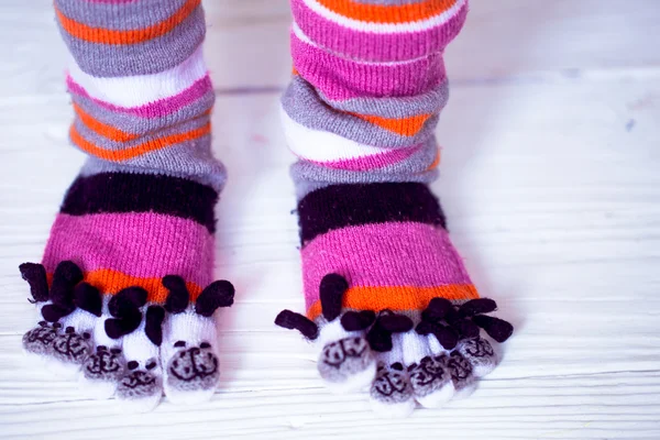 Baby feet in warm, long multicolored socks with toes — Stock Photo, Image