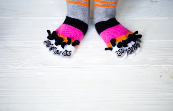 Baby feet in warm, long multicolored socks with toes — Stock Photo, Image