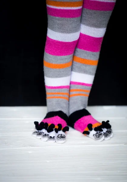 Baby feet in warm, long multicolored socks with toes