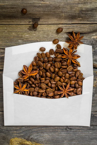 Envelope branco ao ar livre com grãos de café no fundo de madeira — Fotografia de Stock