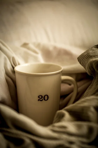 Grande tasse avec boisson chaude au lit — Photo