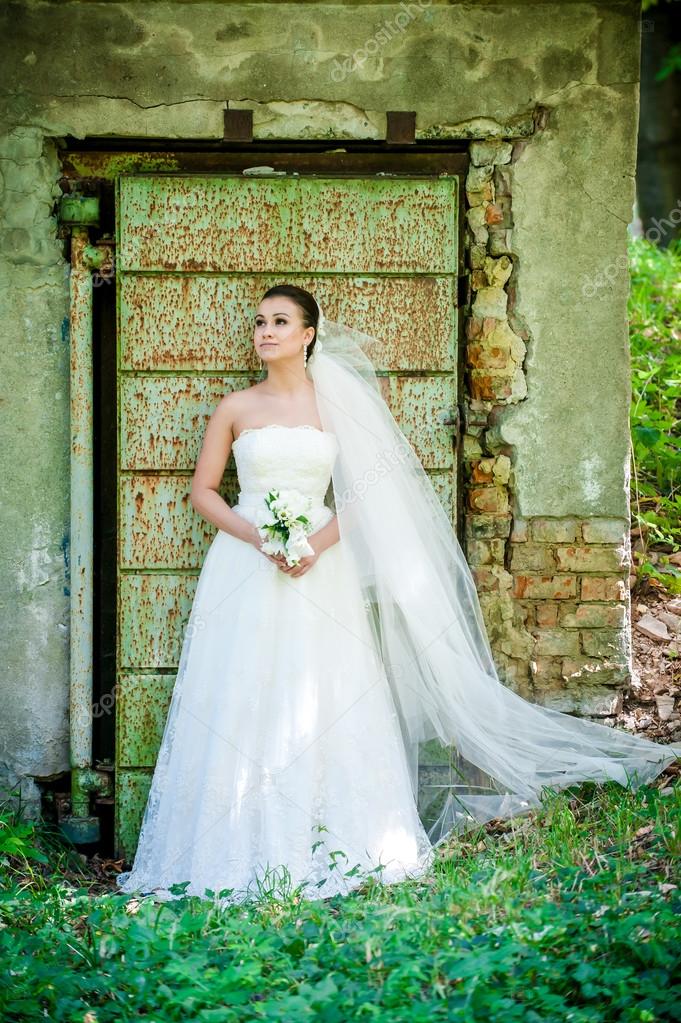 hermosa chica en vestido de novia junto a la puerta vieja — foto de