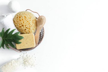 Banyo aksesuarlarıyla dolu bir hayat. Sepette bir bez, bir sabun fırçası, bir havlu, beyaz deniz tuzu beyaz arka plan fotokopi alanı, üst görünüm.