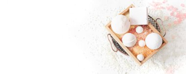 Beyaz arka plan manzaralı ahşap bir kutuda deniz tuzu, banyo bombası ve sabun kompozisyonu.