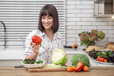 Güzel esmer gülümseme ve lahana kesme modern mutfak arka planında salata için..