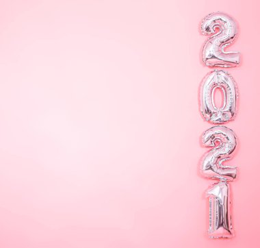 Açık pembe arka plan ve gümüş balonlar sağ tarafta 2021 numara, yeni yıl konsepti.