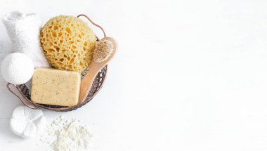 Banyo aksesuarlarıyla dolu bir hayat. Sepette bir bez, bir sabun fırçası, bir havlu, beyaz deniz tuzu beyaz arka plan fotokopi alanı, üst görünüm.