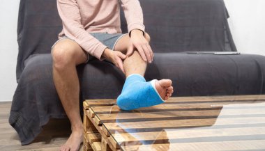 Kanepede bacağı kırık bir adam var. Topuk ya da ayak kemikleri kırılmış. Alçıya alınmış, tıbbi konsept geçmişi var..