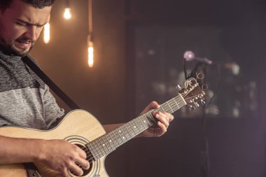 Konserde gitarist akustik gitarı bulanık karanlık arka plana karşı çalıyor..