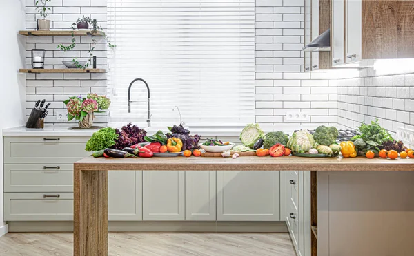 各种蔬菜放在木制桌子上 以现代化厨房的内部为背景 — 图库照片