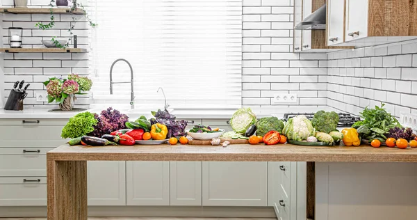 各种蔬菜放在木制桌子上 以现代化厨房的内部为背景 — 图库照片