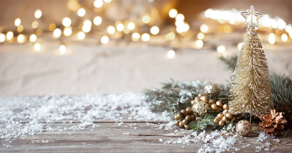 Winter cozy background with festive decor details, snow on a wooden table and bokeh. The concept of a festive atmosphere at home.