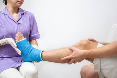 Hastanede bandajlandıktan sonra bir adamın bacağını alçıyla ve mavi bir bantla kapat..