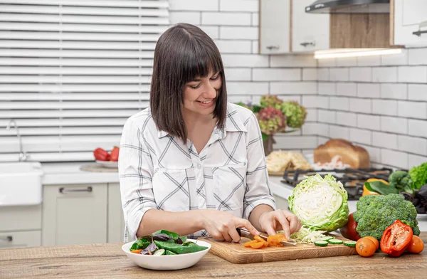 Schöne Brünette Lächelt Und Schneidet Gemüse Auf Einem Salat Vor — Stockfoto