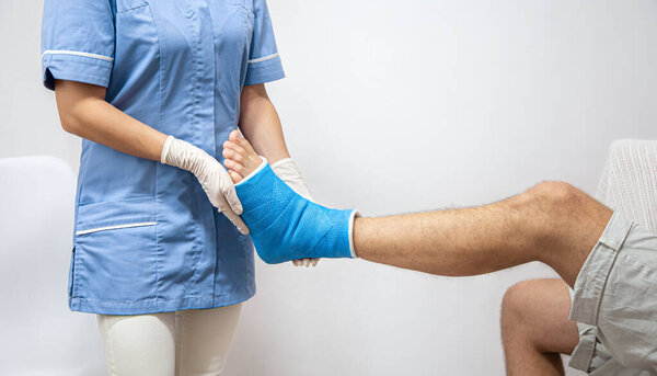 Close up of a man's leg in a cast and a blue splint after bandaging in a hospital.