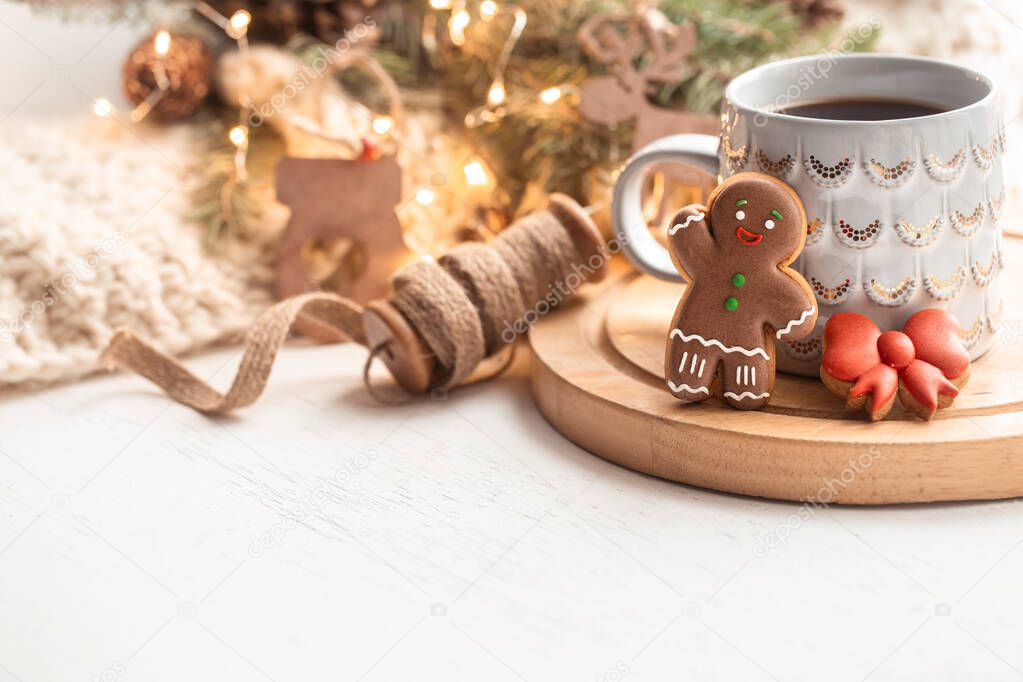 A beautiful cup with gingerbread cookies decorated with glaze close up on a blurred background with decor.