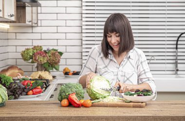 Güzel esmer gülümseme ve lahana kesme modern mutfak arka planında salata için..