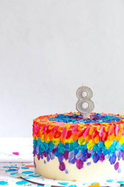 Kremayla süslenmiş çok renkli doğum günü pastası ve sekiz numara. Çocukların doğum günü konsepti.