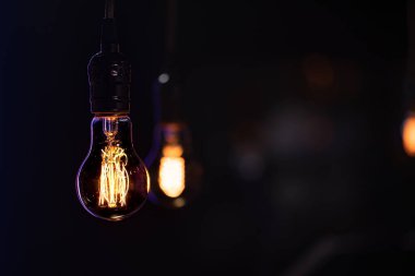 Karanlıkta yanan bir lamba bulanık bir arkaplanda asılı duruyor..