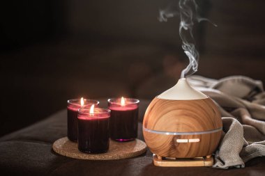Yağ yayıcı, yanan mumların yanında bulanık arkaplanda. Aromaterapi ve sağlık hizmeti kavramı.
