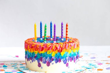 Krem ve mumlarla süslenmiş çok renkli doğum günü pastası. Doğum günü partisi konsepti.