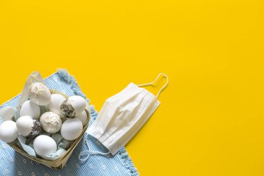 Koronavirüs kopyalama alanından korunmak için maskenin yanında bir sepet Paskalya yumurtası. Paskalya bayramı konsepti.