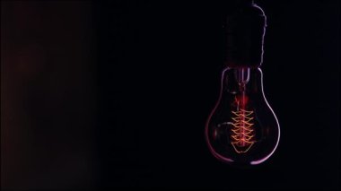 Eski bir ampul karanlıkta pürüzsüz bir şekilde parlamaya başlar. Dekor ve rahat atmosfer kavramı..
