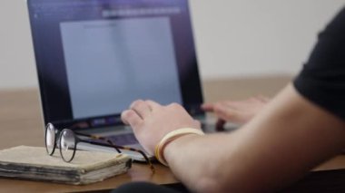 Adam bilgisayarın başında çalışıyor ve iş yerindeki not defterine yazıyor. Çalışma ya da ofis işi konsepti.