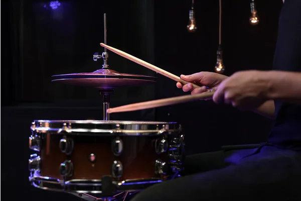 Drummer playing drum sticks on a snare drum in dark. Concert and live performance concept.