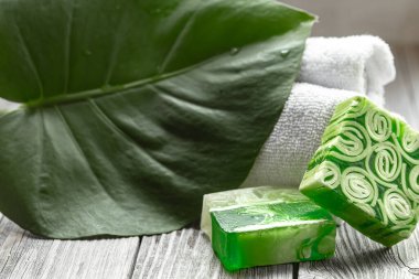 El yapımı sabun, havlu ve büyük yapraklı spa kompozisyonu. Sağlık ve güzellik kavramı.