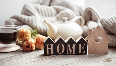 Çiçeklerle dolu şenlikli bir ev, bir fincan çay ve ahşap bir yüzeye yakın dekorasyon ayrıntıları..