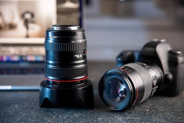 Professional camera and lens close-up on a photographer's desktop on a blurred background. clipart