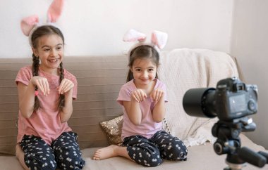 Tavşan kulaklı küçük kardeşler kameraya tavşanları gösteriyor. Paskalya fotoğraf oturumu konsepti.