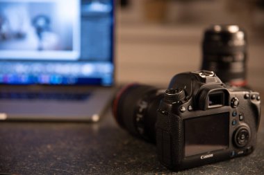 Bilgisayarlı bulanık bir arka planda profesyonel kamera. Fotoğraflar ve videolarla çalışma kavramı.