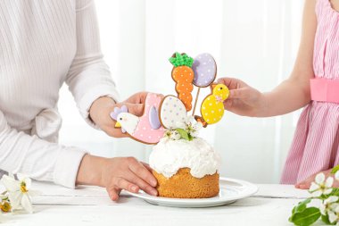 Anne ve kızı pakhsal pastasını süslüyor. Aile tatiline hazırlanma konsepti Paskalya için.