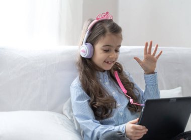 Koronavirüs salgını nedeniyle karantina sırasında internetten alınan bir derste evde dizüstü bilgisayarla oturan bir ilkokul öğrencisi..