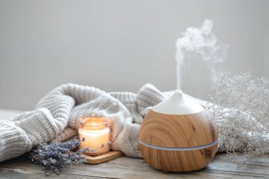 Ahşap bir yüzey üzerinde, örülmüş bir element, mum ve lavanta içeren modern aroma yağı yayıcı ile Aroma bileşimi.