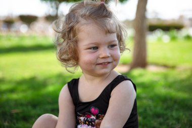 Yazın bahçede çimlerin üzerinde oturan komik küçük kız..