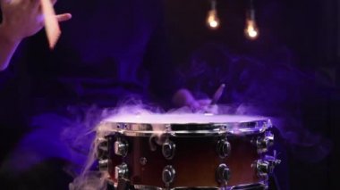 Baterist davulda sopalarla çalar dumanla ve karanlıkta güzel bir aydınlatmayla.