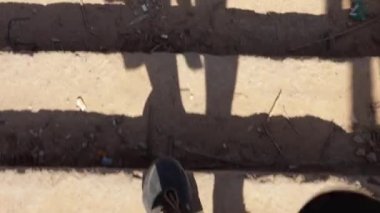 Spor ayakkabılı erkek ayakları sıcak bir günde terk edilmiş bir binanın kumlu merdivenlerinde yürüyor..