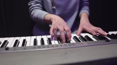 Karanlık bir arka planda piyano çalan bir kadının yakın çekimi. Pratik konsepti, müzik kaydı, performans.
