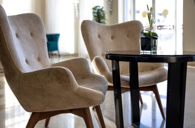 Masanın yanında beyaz döşemeli güzel sandalyeler ve bir buket çiçek. Oda tasarımı fikri.