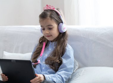 Koronavirüs salgını nedeniyle karantina sırasında internetten alınan bir derste evde dizüstü bilgisayarla oturan bir ilkokul öğrencisi..