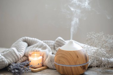 Ahşap bir yüzey üzerinde, örülmüş bir element, mum ve lavanta içeren modern aroma yağı yayıcı ile Aroma bileşimi.