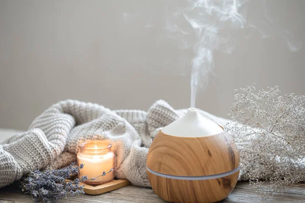 Ahşap bir yüzey üzerinde, örülmüş bir element, mum ve lavanta içeren modern aroma yağı yayıcı ile Aroma bileşimi.