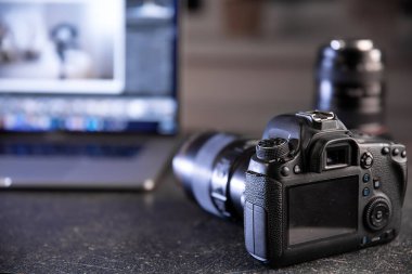Bilgisayarlı bulanık bir arka planda profesyonel kamera. Fotoğraflar ve videolarla çalışma kavramı.