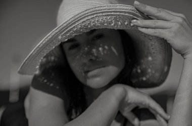 Güneşli bir günde hasır şapka takan baştan çıkarıcı genç bir kadın. Tatil ve yaz konsepti. Siyah beyaz fotoğraf.