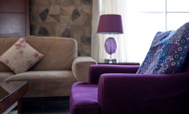 Oturma odasının içinde rahat koltuklar, masa lambası ve pencerenin yanında yer lambası var. Oturma odası tasarımı fikri.